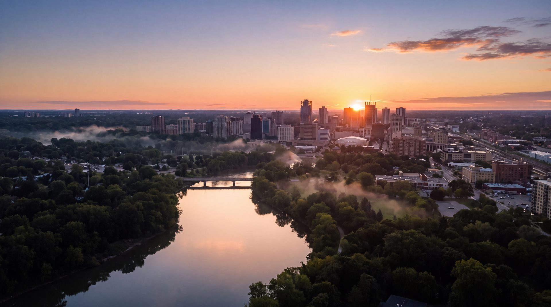 Aerial view of London, Ontario at sunrise, the Thames River glowing as it winds toward the downtown skyline